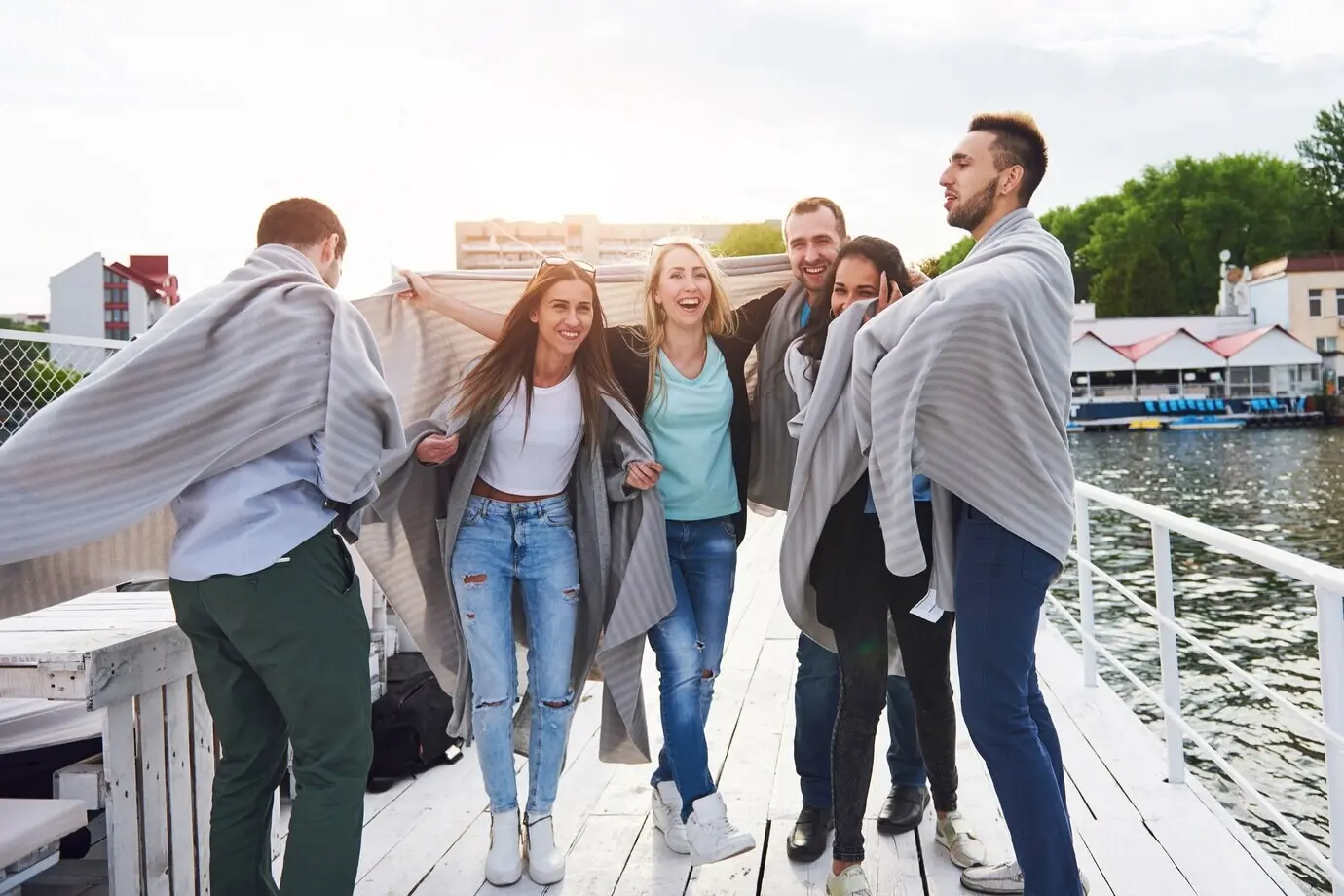 Lächelnde, glückliche Gruppe von Freunden, die im Freien auf dem Pier am Strand posiert.